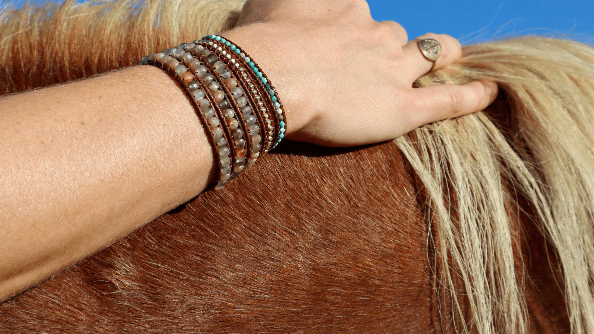 girl's arm with bracelets laying on a horses back